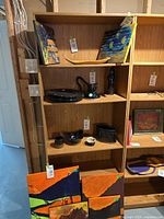 Photo of the bookshelf filled with various decorative items and small artworks, showing the faux light wood finish and shelving configuration.