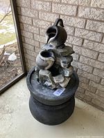 Fountain full view showing black base, grey pots, and cascading water design.