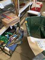 Photo showing plastic garden wheelbarrow, garden gloves, trowels, and Costco garden paper bags on shelving near gardening supplies.