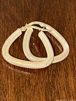 Both earrings shown front-facing, stacked display of triangular hoop shape.