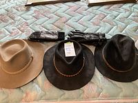 Three hats and two pairs of gloves laid out on bedspread