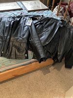 Three black leather jackets displayed on a mattress