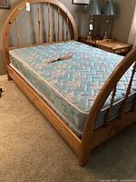 Pine double bed with mattress, curved headboard with spindle design, visible scratches on wood.