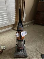 Full view of Hoover Windtunnel upright vacuum cleaner showing transparent dirt canister and ergonomic handle with manual attached.