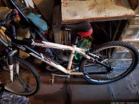 Side view showing the white aluminum frame Nakamura Shockteam bicycle with knobby tires and padded seat in a garage setting