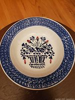 Top view of the antique ceramic plate showing blue spongeware border and red and blue floral basket in the center