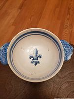Top view of the antique Quimper soup bowl showing the Fleur De Lys symbol painted in blue on the white glazed interior with a double blue line near the rim and blue handles.