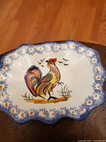 Top view of handpainted ceramic platter with colorful rooster and floral blue border.