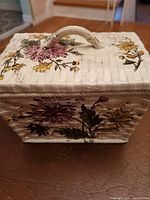 Side view of antique ceramic box showing floral pattern and handle