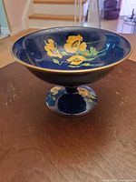 Front side view of the dark blue Royal Winton compote dish with yellow floral decorations and gold trim.
