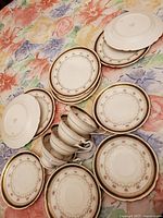 Top view of assorted Shelley china dinnerware pieces including plates and cups arranged on a floral tablecloth.