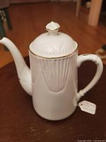 Photo of white fine bone china Shelly teapot with embossed vertical leaf detailing, gold rim and finial top.