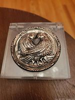 Front view showing sterling silver top with two birds forming a heart shape in the center of the compact.