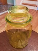 Top view of vintage green glass apothecary jar with rounded glass lid showing smooth finish and transparent yellow-green tint.