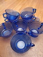 Top view of six cobalt blue glass cups stacked and arranged to show ribbed pattern and handles