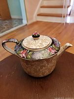 Full view of vintage floral teapot with gold speckled lower body and floral decorated top and lid.