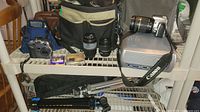 Overview of the lot showing cameras, lenses, projector, camera bags, and tripods on shelf