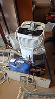 Hisense dehumidifier, heater, window fan, and ultrasonic humidifier grouped on floor with cords visible