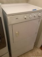 Full front and angled view showing the Kenmore dryer with white finish and bottom stand.