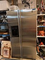 Full front view of the stainless steel GE Profile side-by-side refrigerator in indoor environment, showing doors and handles.