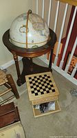 Full view of the globe on the stand with the games box adjacent showing the chess/checkers board top and open bottom with game pieces inside.