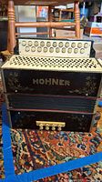 Front view of Hohner accordion on patterned carpet, showing buttons and floral design.