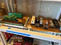Nine model train cars displayed on a metal shelf, including green Lehigh Valley cars and older metal cars with visible wear and scratches.