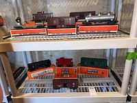 Shelf view of nine cars in original Lionel boxes