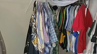 Full view of men's shirts and t-shirts hanging on a rod showing various colors, patterns, and styles all in size large.