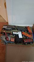 Overview of the tinplate train set showing all the train cars arranged in original box. Visible are different engines and cars including Pennsylvania and Rock Island labeled cars.