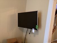 Samsung black flat-screen TV mounted on wall with cables hanging down.