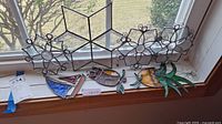 Wide view of all stained glass pieces arranged on windowsill including the plant, owl, sailboat, and three star shapes