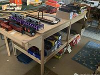 Overall view of wooden train table with model trains and train boxes on top and underneath