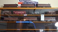 Multiple shelves displaying 10 O gauge model train cars including Pennsylvania passenger coaches and Lehigh Valley freight cars