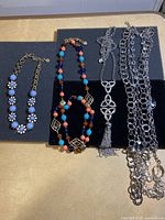 All four necklaces displayed together on black and beige background.