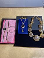 Overview of wristwatch and bracelets on pink background, two necklaces displayed on blue and black backgrounds