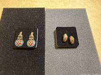 Two pairs of Heidi Daus earrings on black display cards showing colors and designs