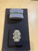 Bracelet and brooch displayed on black foam pad.