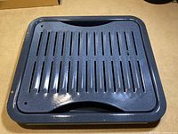 Top view of blue enamel broil pan insert with long slots and handle cut-out