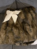 Faux fur blanket folded with ivory bow on dark couch