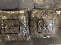 Two new foul fur throw pillows in packaging with Guillaume Home branding, shown side by side