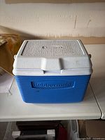 Front side of Rubbermaid cooler showing blue body and white lid with Rubbermaid logo