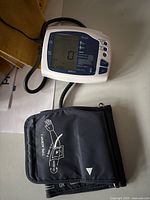 Front view of Rexall digital blood pressure monitor displaying 0 with tube and arm cuff lying adjacent