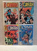 Four Conan the Barbarian comic books laid out on a flat surface showing colorful covers with Conan in battle scenes and other characters.