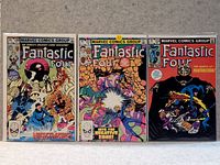 Photo showing three of the Fantastic Four comic books flat on a surface, displaying their front covers with colorful artwork and the Marvel Comics Group logo.