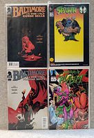 Top-down photo of four comic books laid out flat, showing their front covers clearly. Comics include two Baltimore series, Spawn #1, and Warriors of Plasm #3.