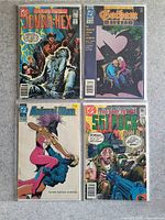 Photo of four comic books: Jonah Hex, Gotham Knights, Amethyst, Sgt. Rock in protective sleeves on a grey surface.