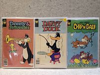 Photo of three collectible comic books featuring Tweety & Sylvester, Daffy Duck, and Chip 'n Dale in protective sleeves.