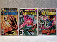 Photo of three Doctor Strange comic books side by side laying flat on carpeted floor, each in plastic protective sleeve.