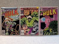 Three Incredible Hulk comic books laid out side-by-side on a gray surface.